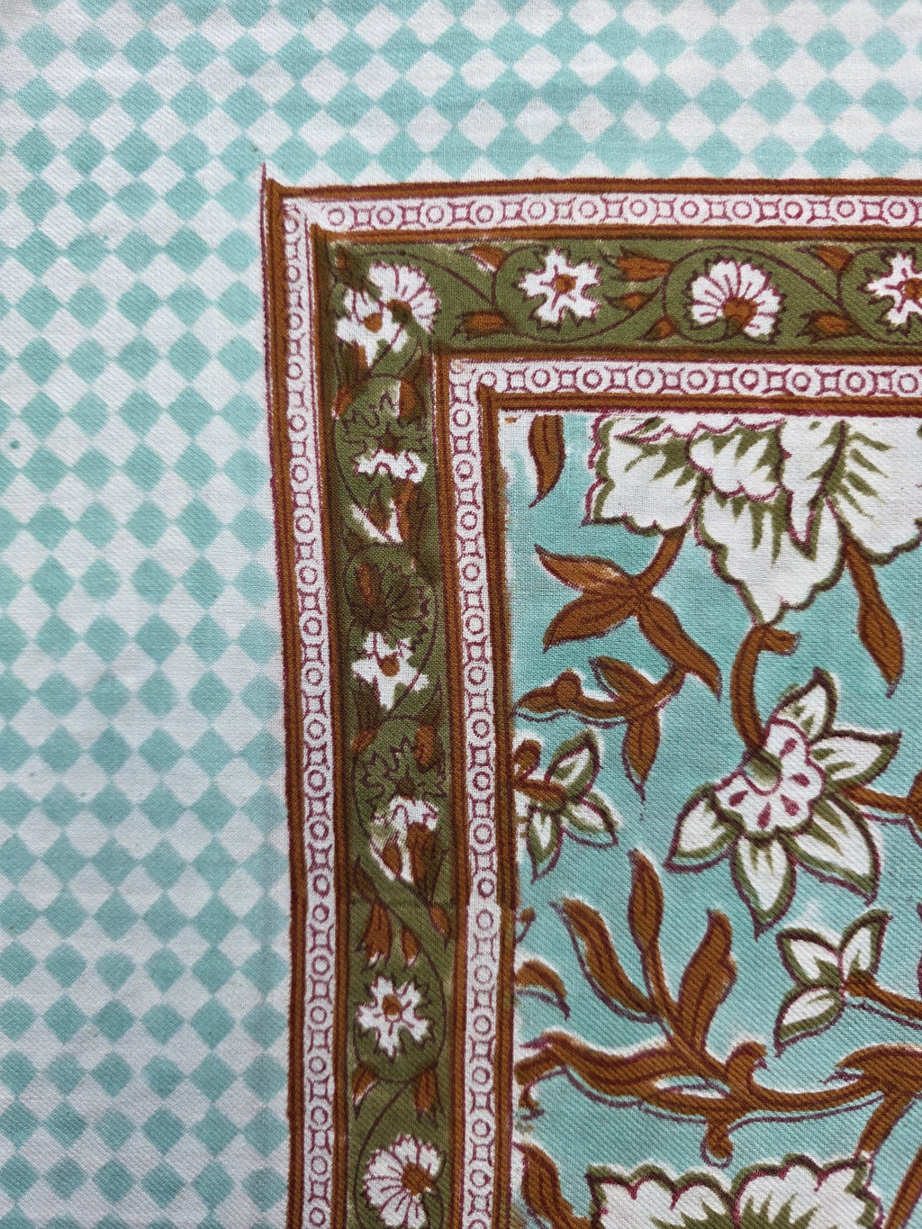 Détail du blockprint du foulard Sarita : damier vert d’eau et bordure fleurie olive