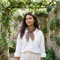 Foulard Sona porté en extérieur, noué au cou sous une pergola de jardin