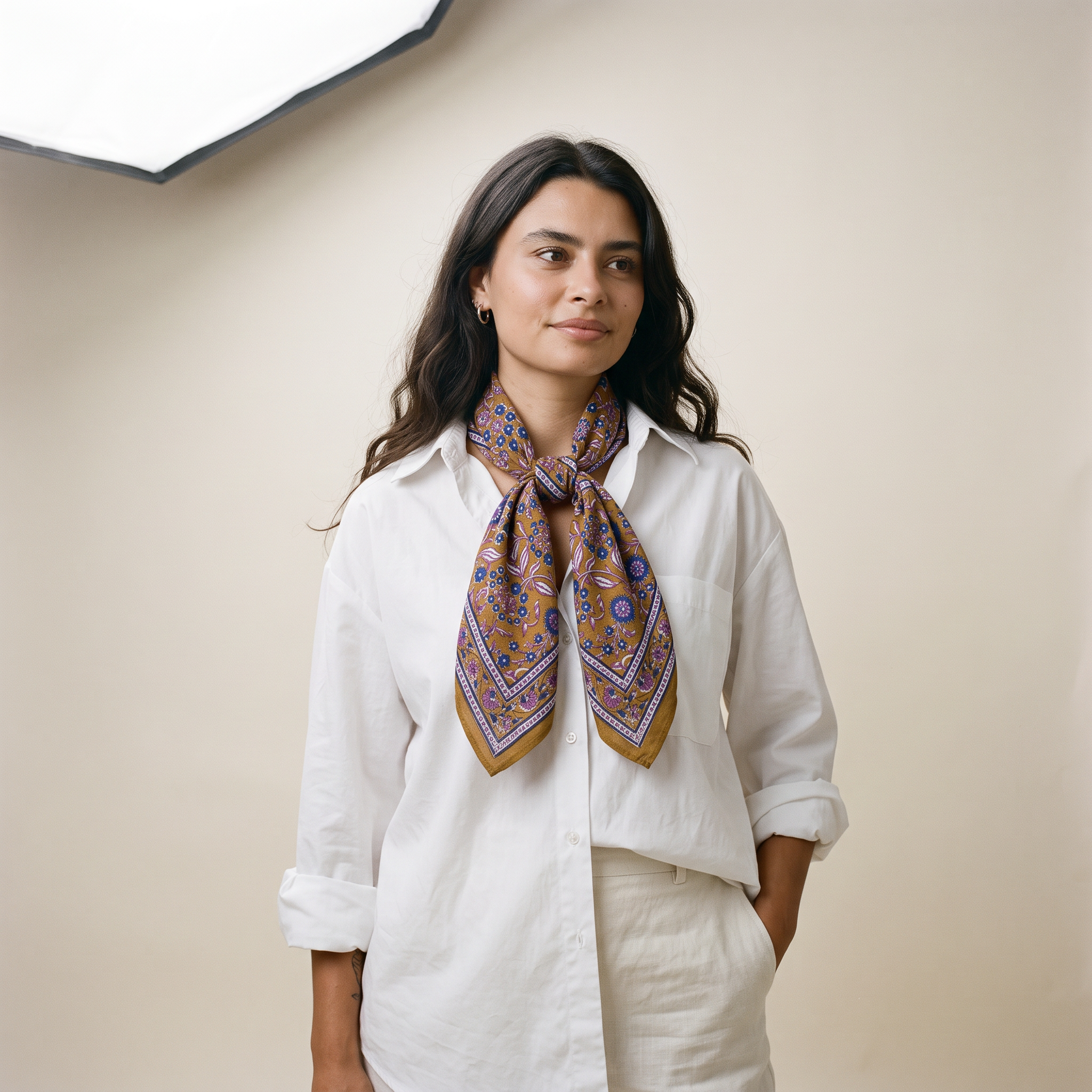 Foulard Sona porté : noué au cou sur une chemise blanche, fleurs violettes sur ocre