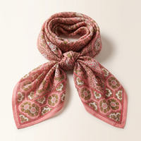 Foulard Lalima noué : voile de coton rose, feuillage olive et fleurs blanches, bordure à rosaces