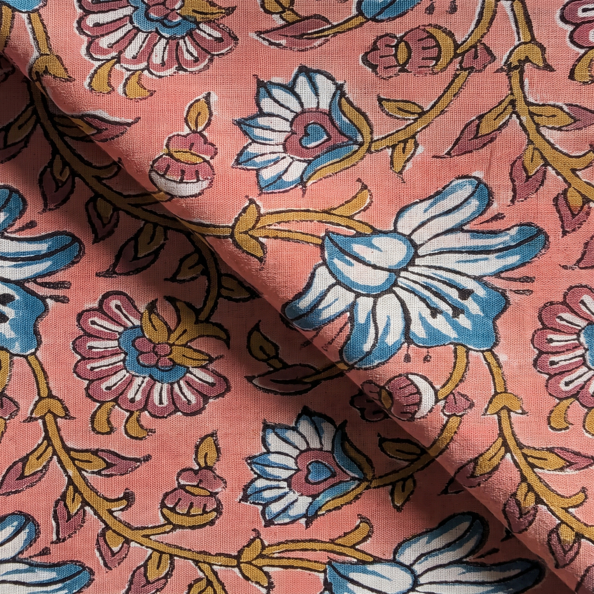 Détail du blockprint du petit foulard Usha : trame du voile de coton, fleurs bleu pétrole et volutes ocre sur rose corail
