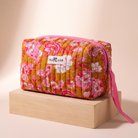 Trousse de toilette Anjali en coton matelassé blockprint ocre et rose, posée sur son socle