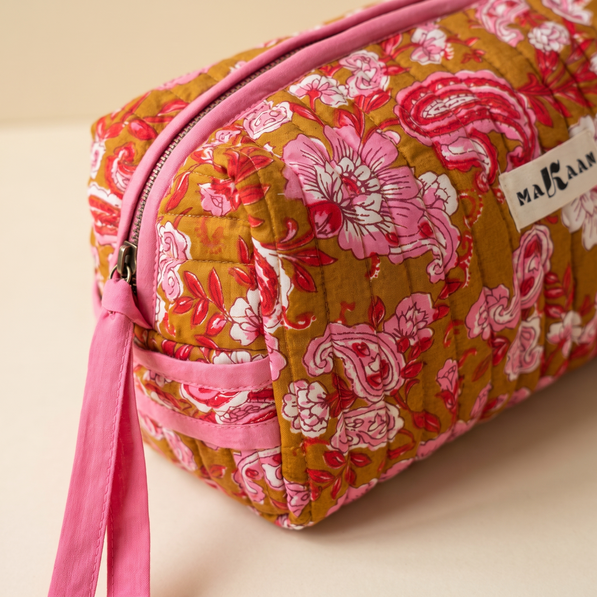Détail de la trousse Anjali : matelassage vertical, zip et ruban de coton rose