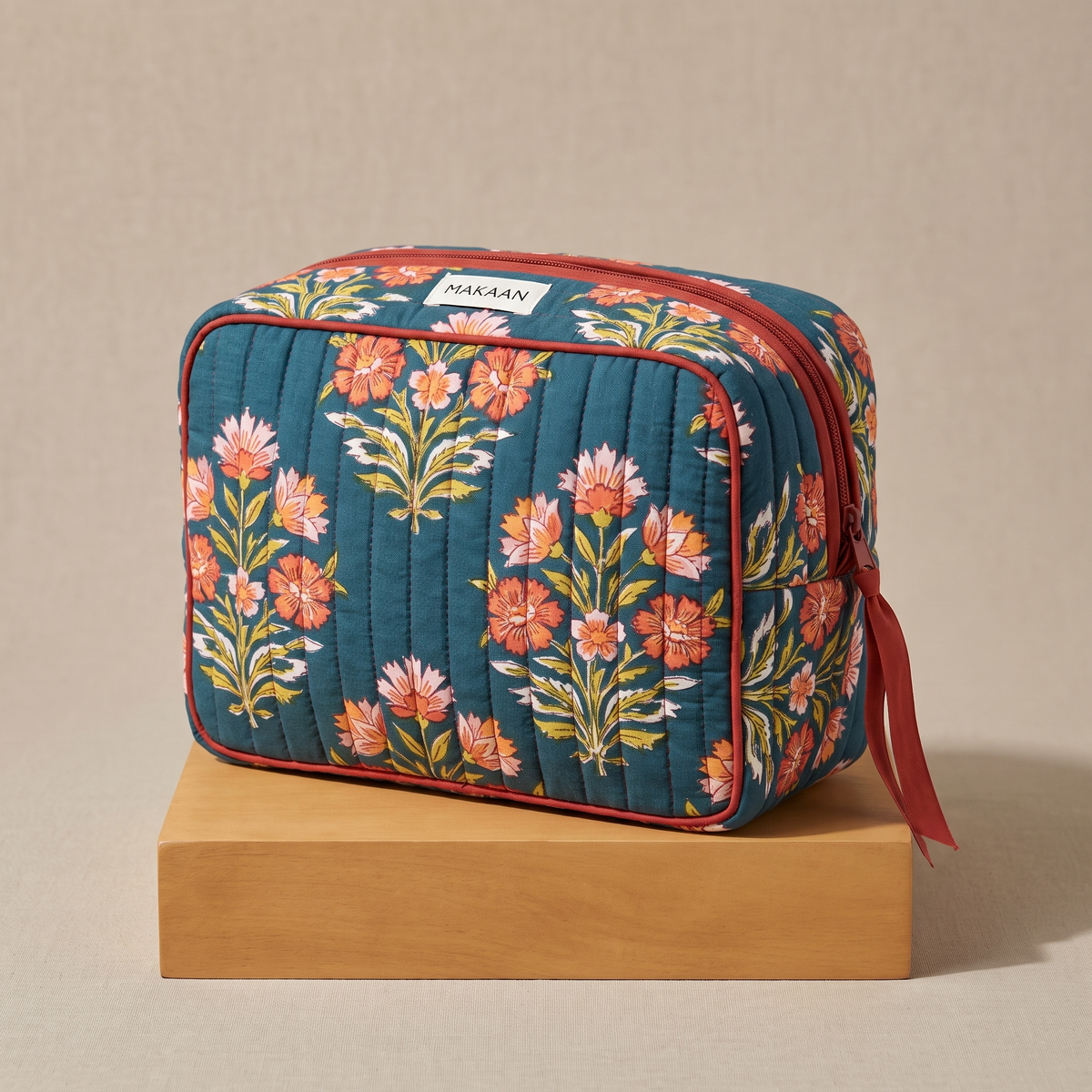 Trousse de toilette Ambar en coton matelassé blockprint bleu canard et corail, posée sur son socle