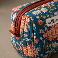 Détail de la trousse Ambar : matelassage vertical, zip et ruban de coton rouge brique