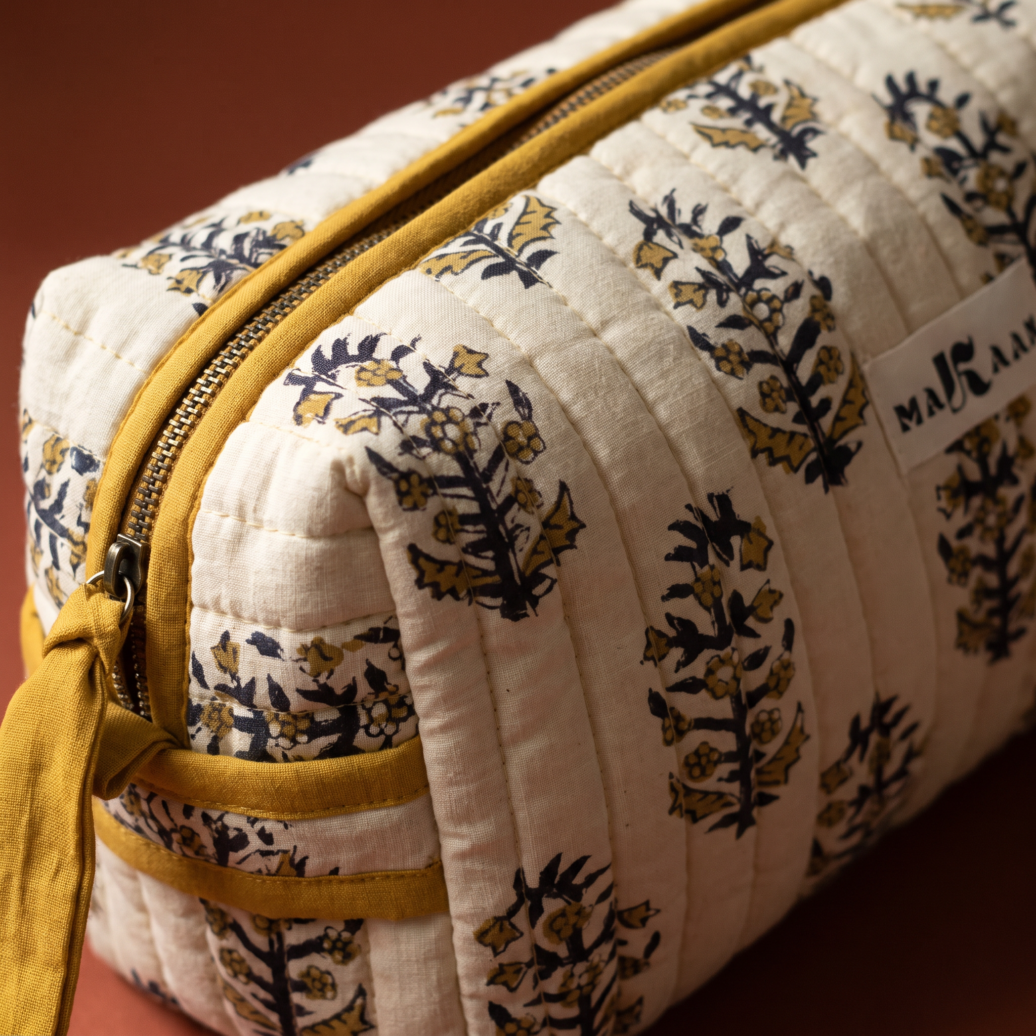 Détail de la trousse Roshni : matelassage vertical, zip et ruban de coton moutarde
