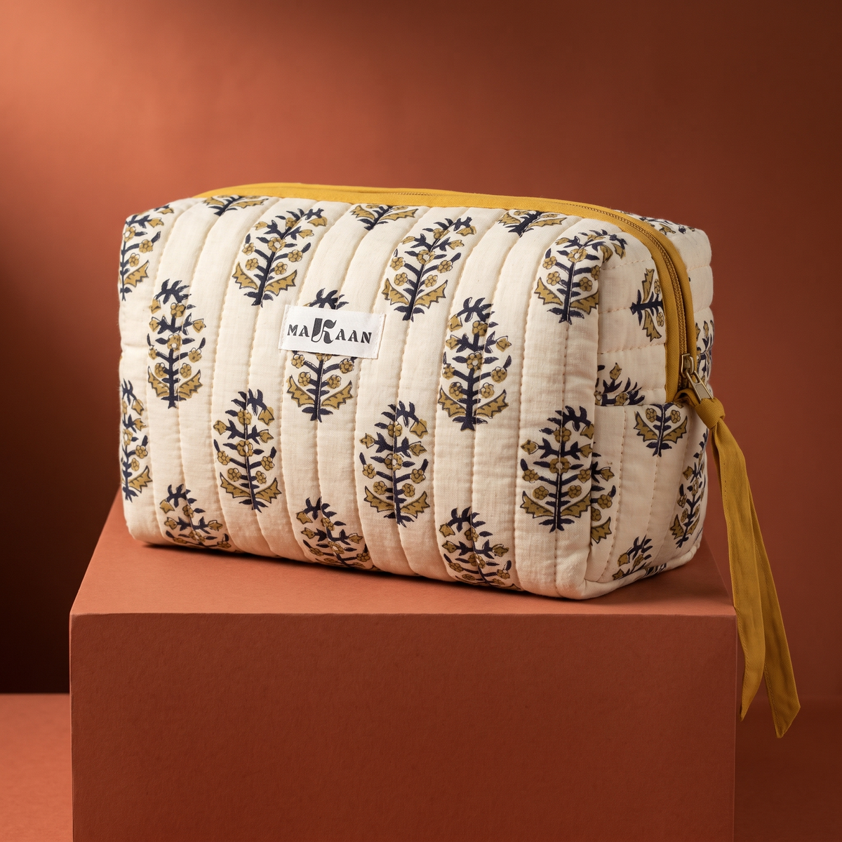 Trousse de toilette Roshni en coton matelassé blockprint crème, olive et marine, posée sur son socle
