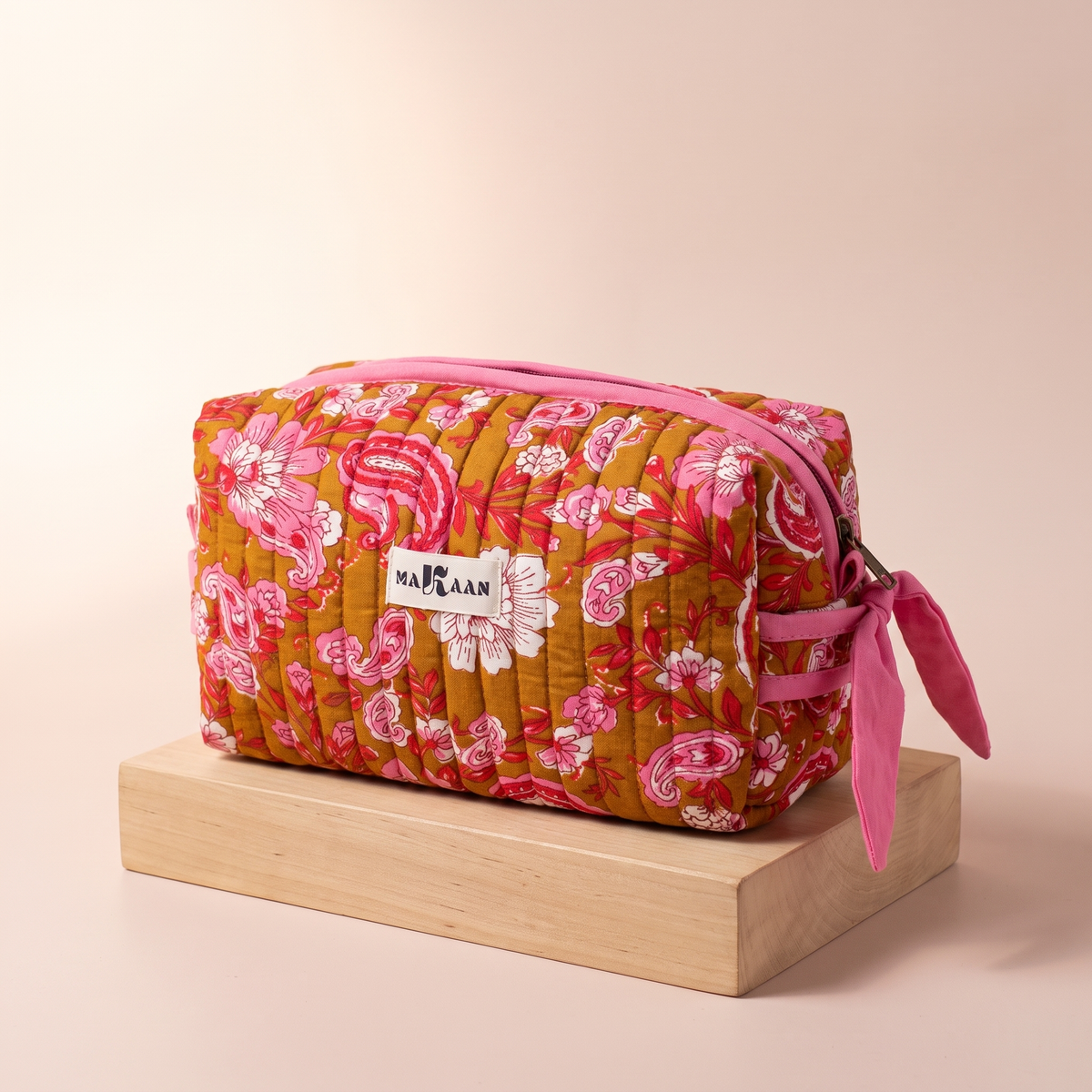Trousse de toilette Anjali en coton matelassé blockprint ocre et rose, posée sur son socle