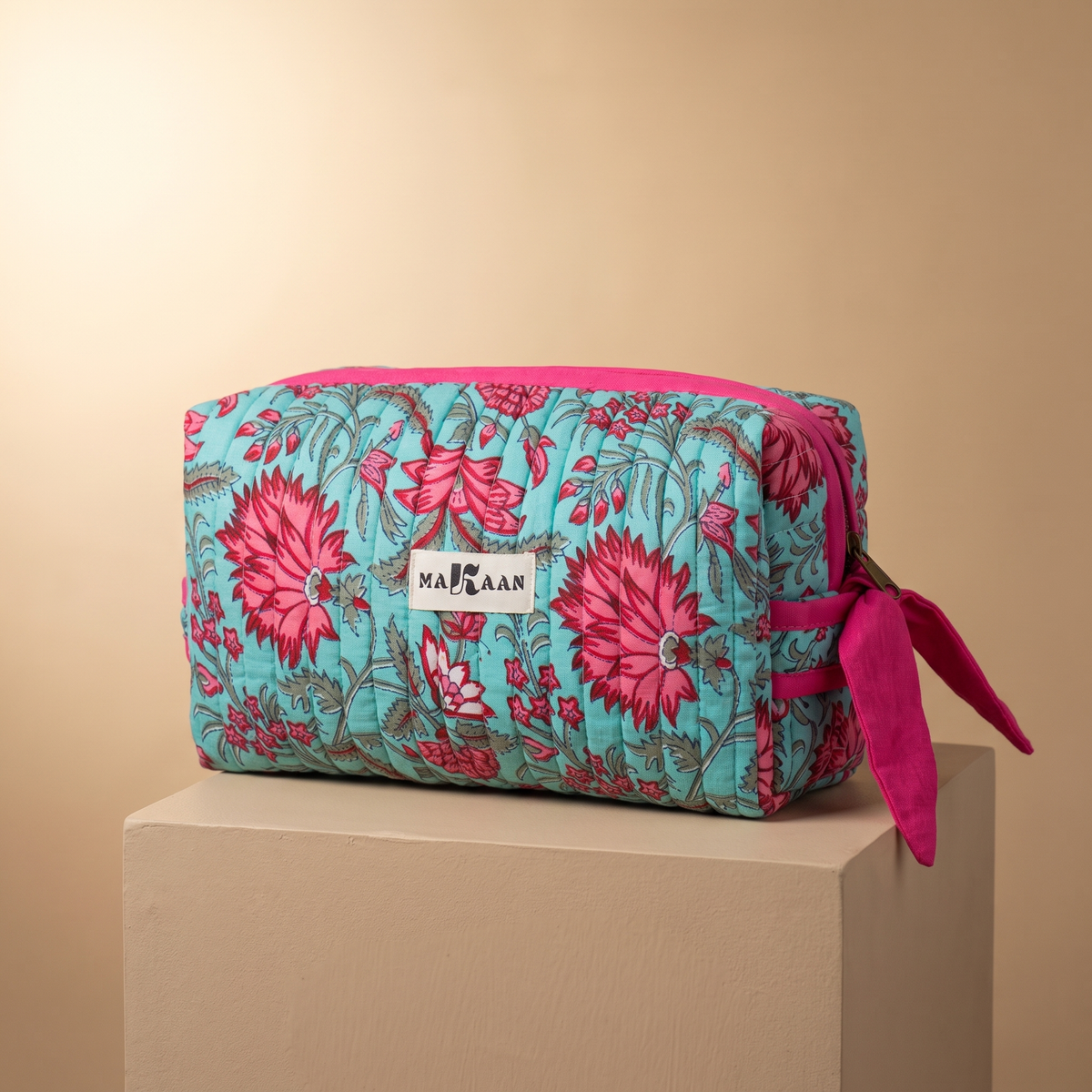 Trousse de toilette Padma en coton matelassé blockprint turquoise et rose, posée sur son socle