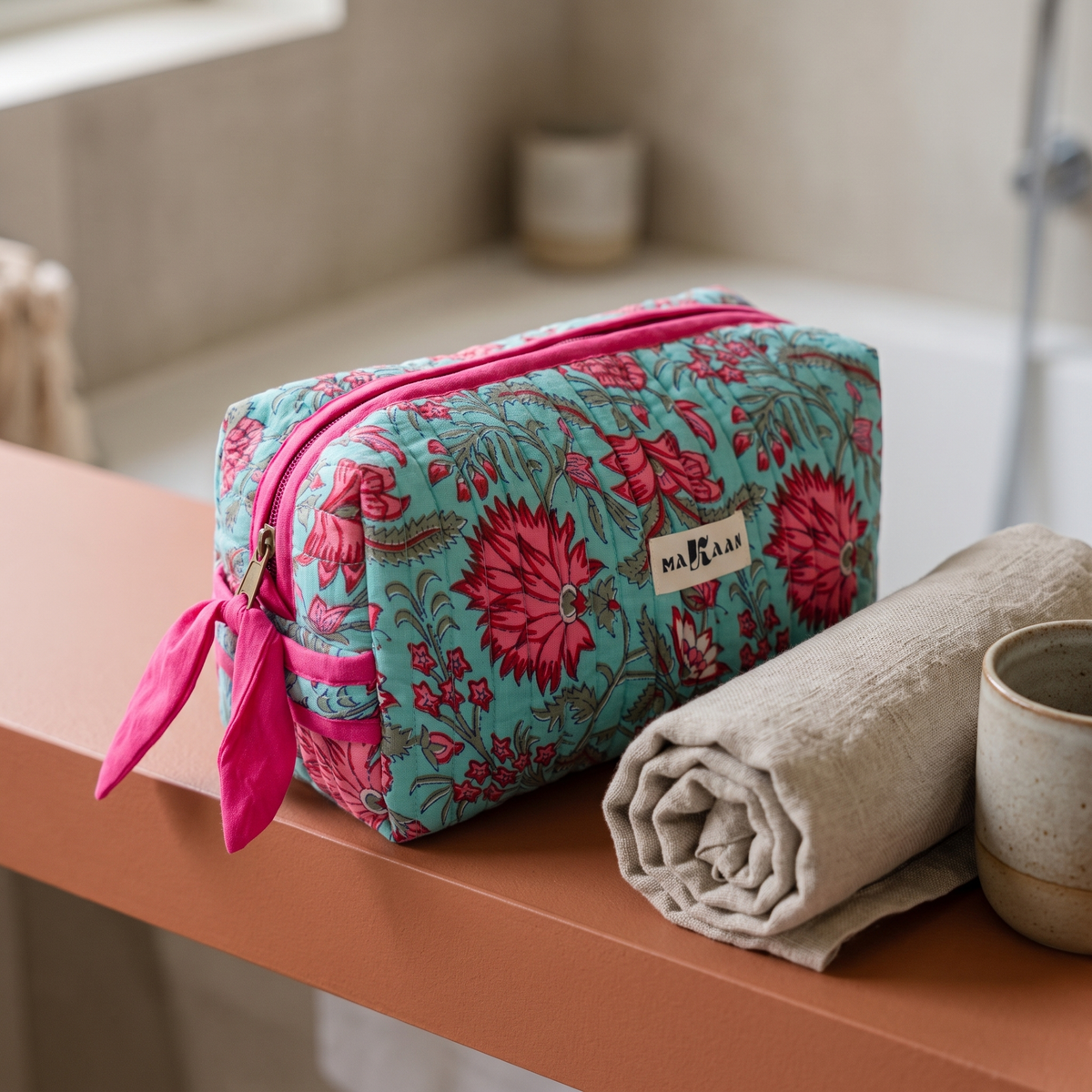 Trousse Padma posée sur une étagère de salle de bain en terre cuite, ruban noué