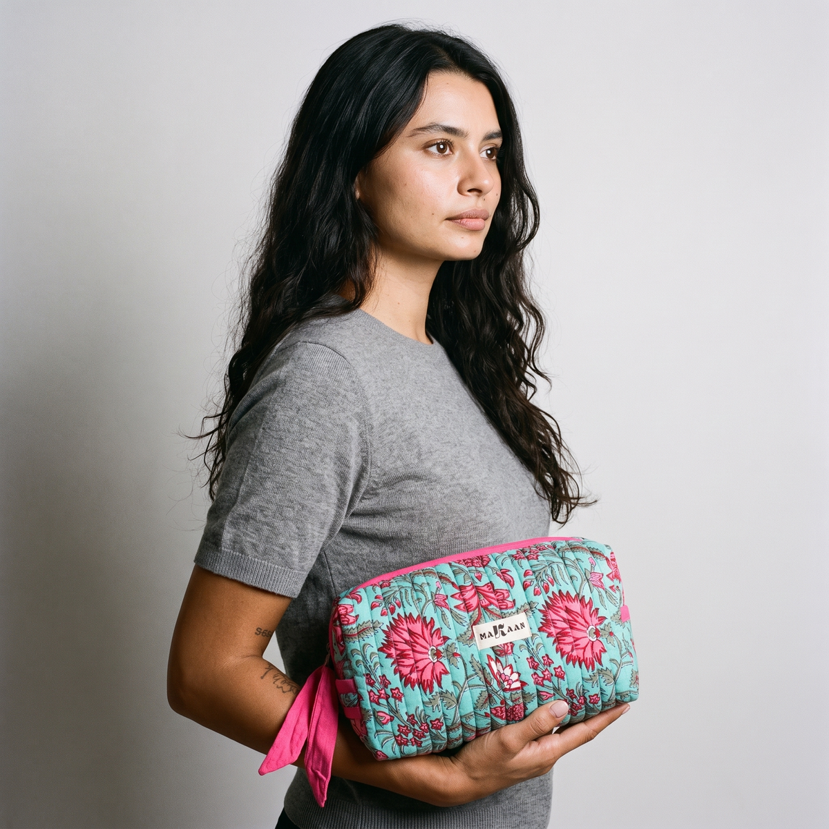 Trousse de toilette Padma portée à la main, le long du corps