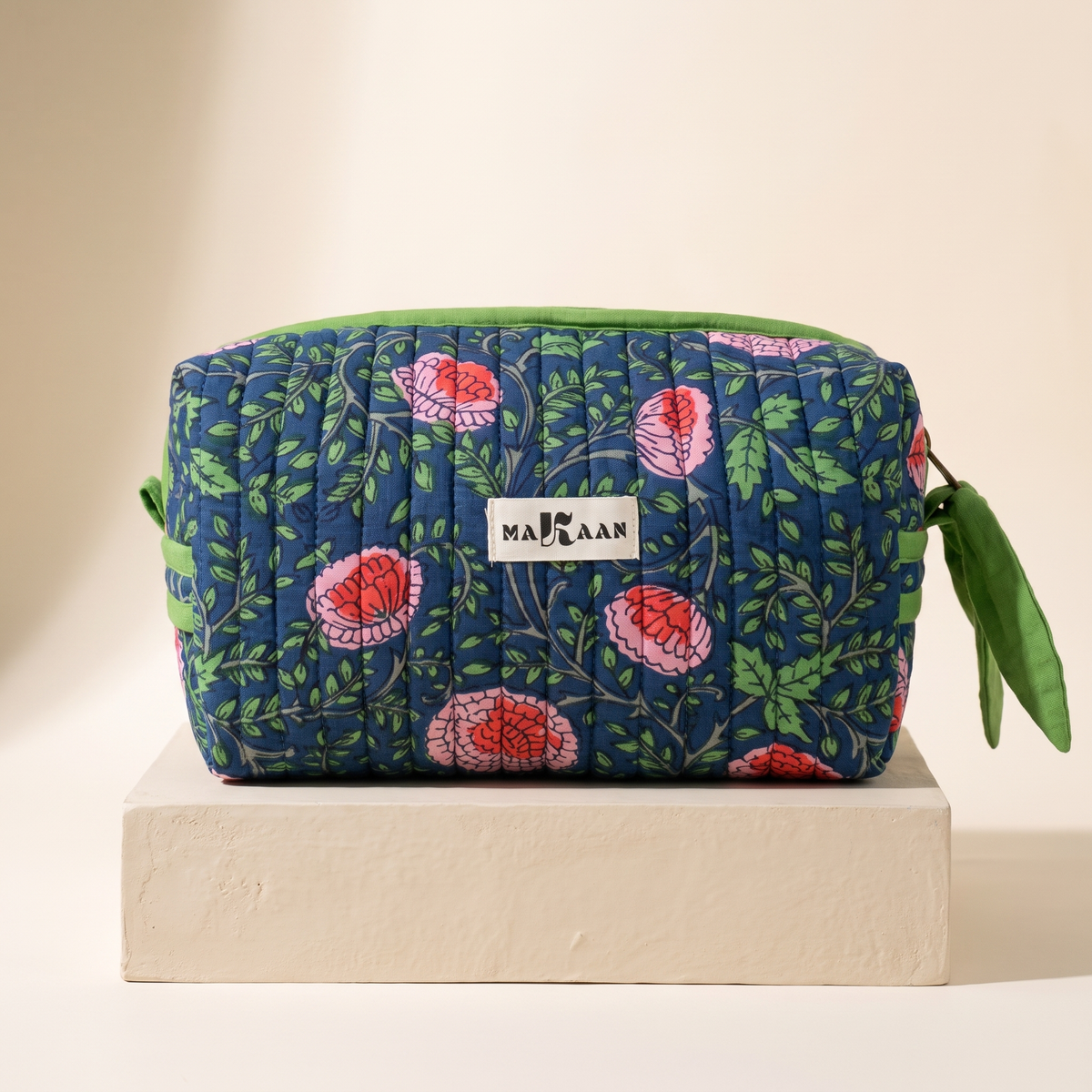 Trousse de toilette Jaya en coton matelassé blockprint bleu de nuit et vert, posée sur son socle