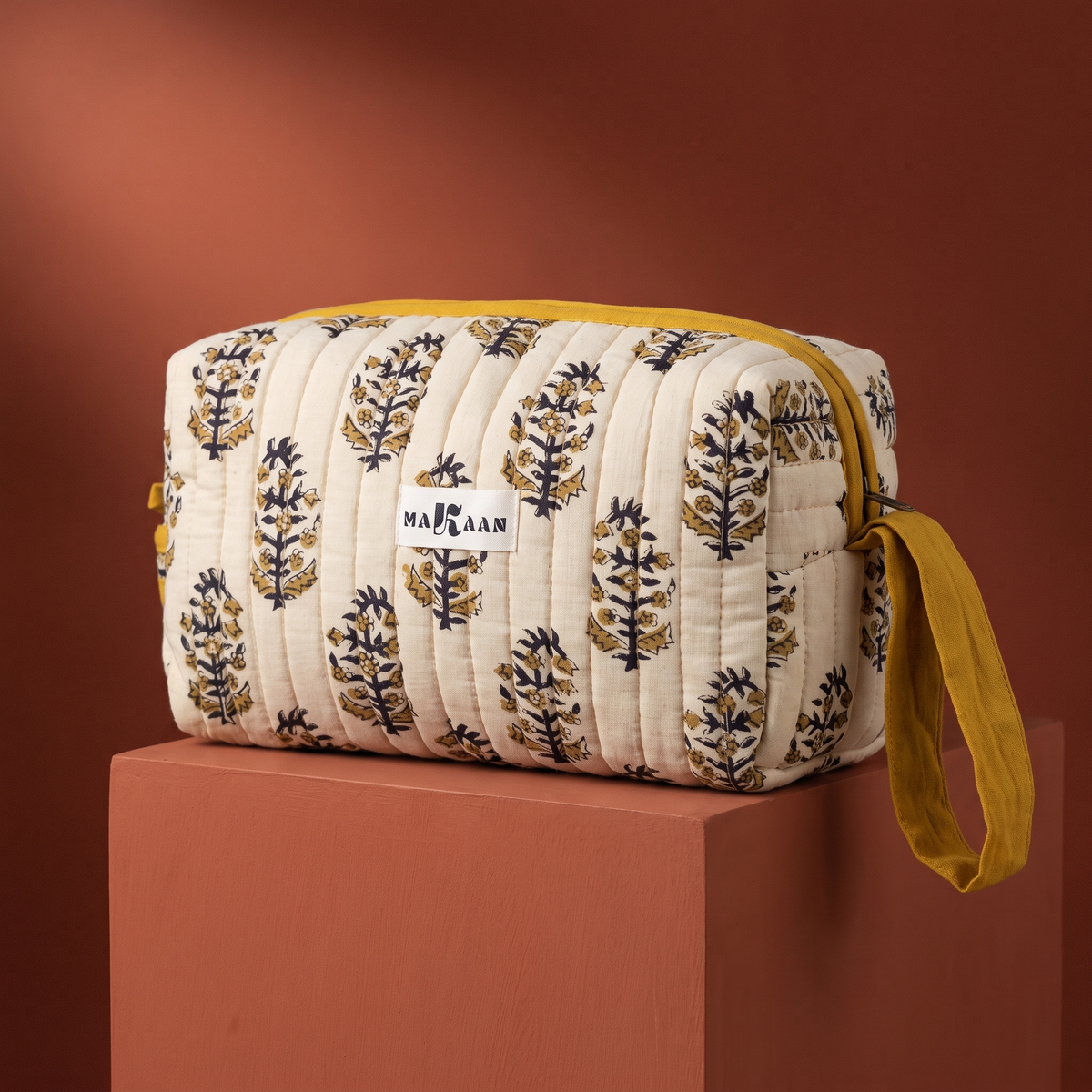 Trousse de toilette Roshni en coton matelassé blockprint crème, olive et marine, posée sur son socle