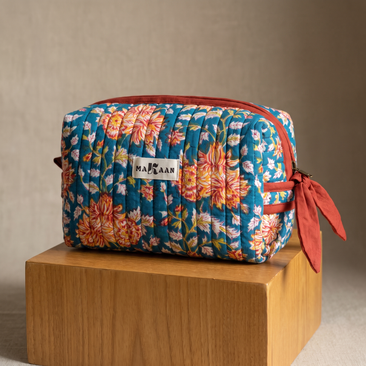 Trousse de toilette Ambar en coton matelassé blockprint bleu canard et jaune safran, posée sur son socle