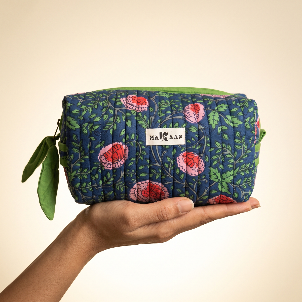 Trousse de toilette Jaya posée sur la paume, sa taille réelle