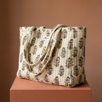 Cabas Chandan en coton matelassé : grand sac blockprint à buti noir et miel sur écru, deux anses en tissu imprimé, posé sur un socle