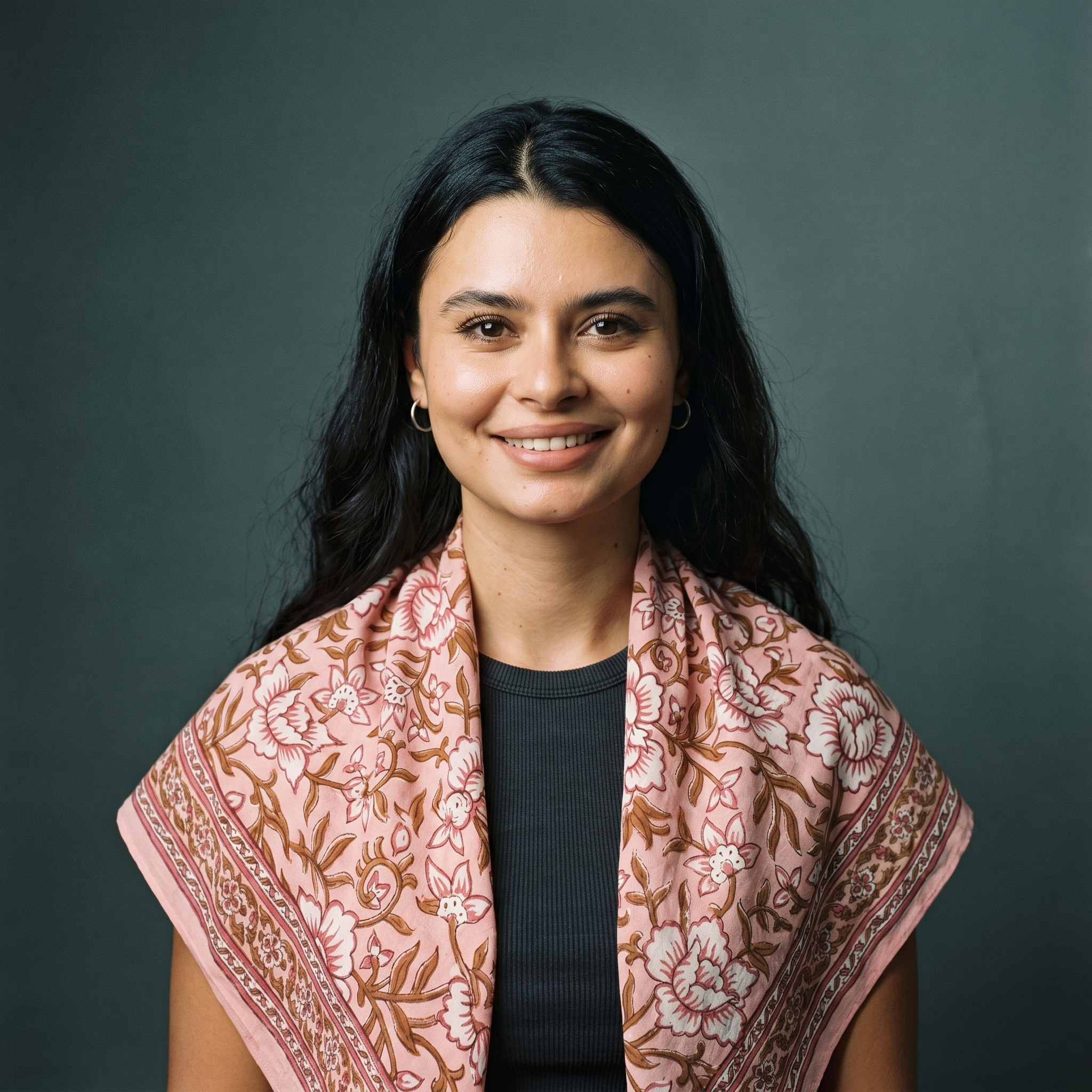 Femme souriante portant le foulard Bagru Blush drapé au cou, rose poudré et fleurs crème sur twill de coton