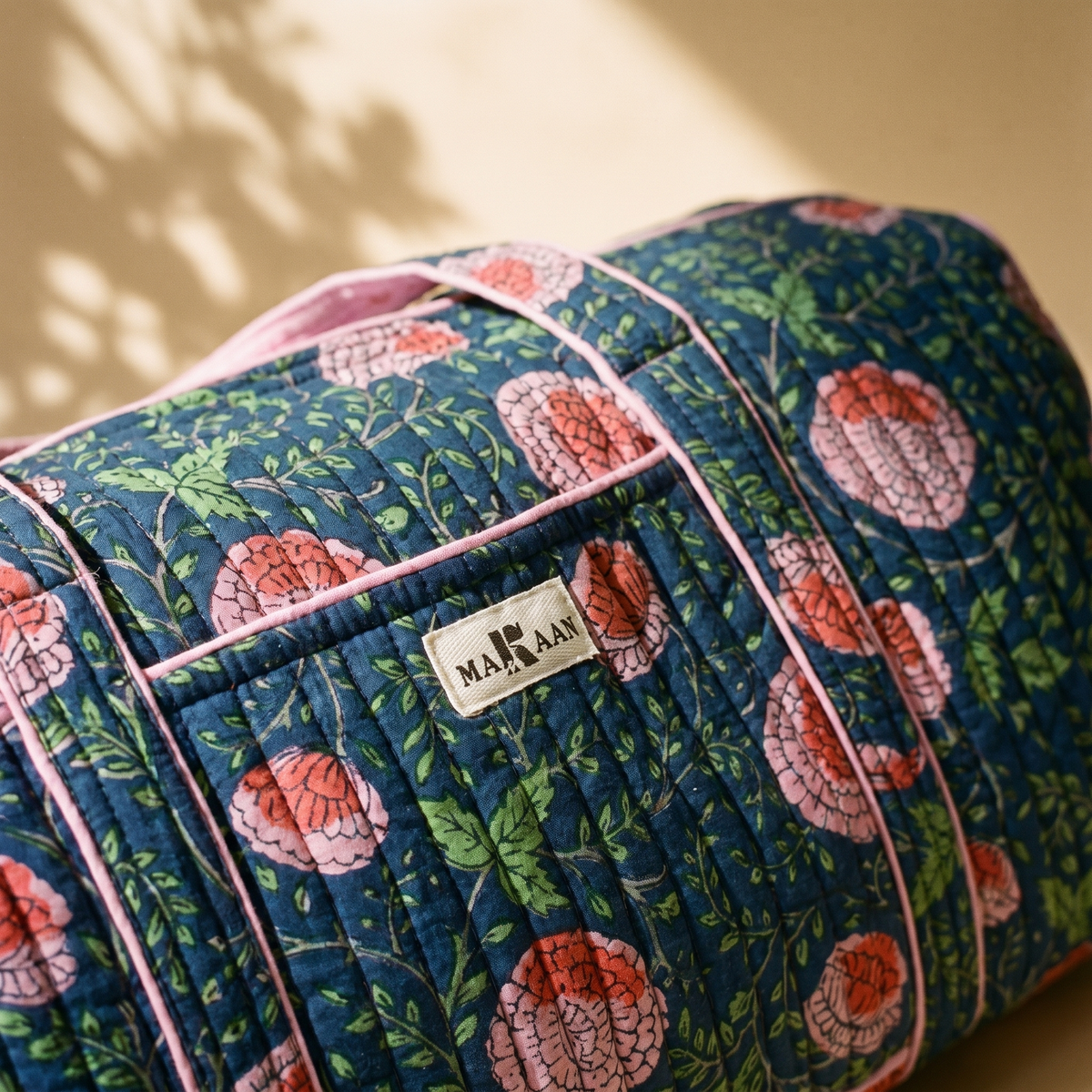 Détail du sac week-end Kusum : blockprint indigo, feuillage vert pomme, étiquette MAKAAN cousue sur la poche et biais rose