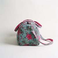 Sac week-end Nilofar vu de bout : panneau latéral arrondi bordé de fuchsia, boucle en laiton de la bandoulière