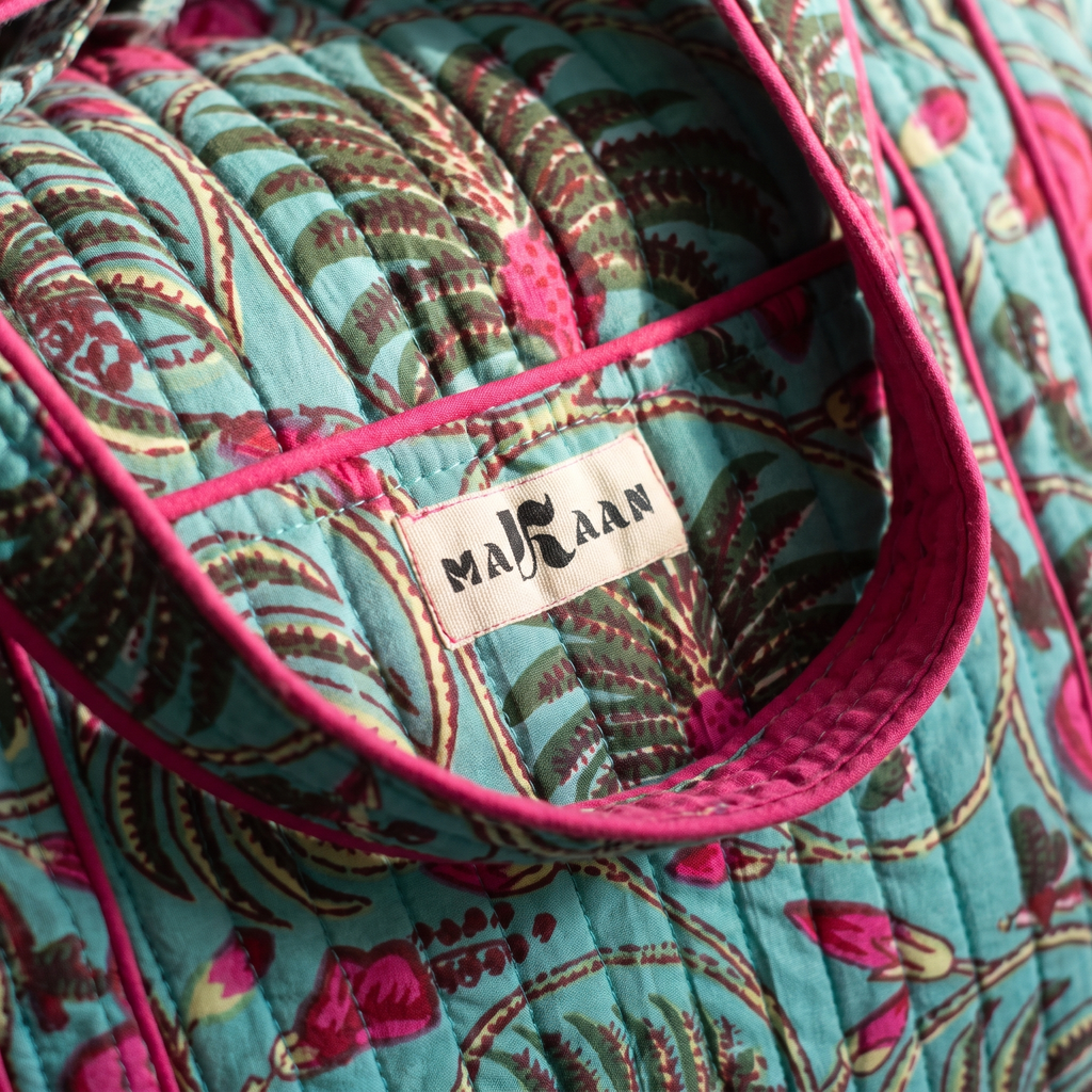 Détail du sac week-end Nilofar : blockprint turquoise et fougères, étiquette MAKAAN sur la poche, biais fuchsia