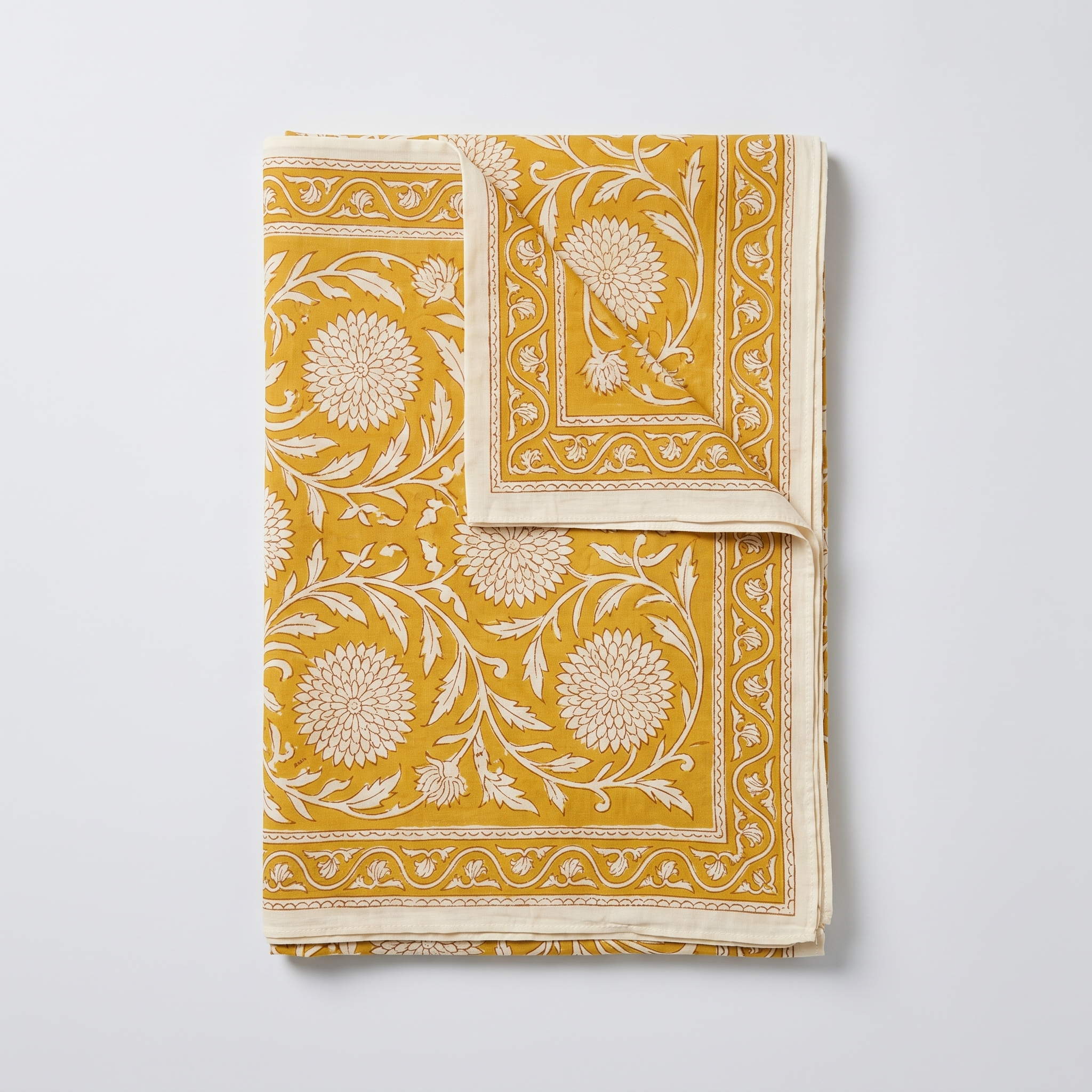 Paréo Haldi plié à plat : coton blockprint, fleurons crème réservés sur jaune curcuma, bordure à dents et liseré écru