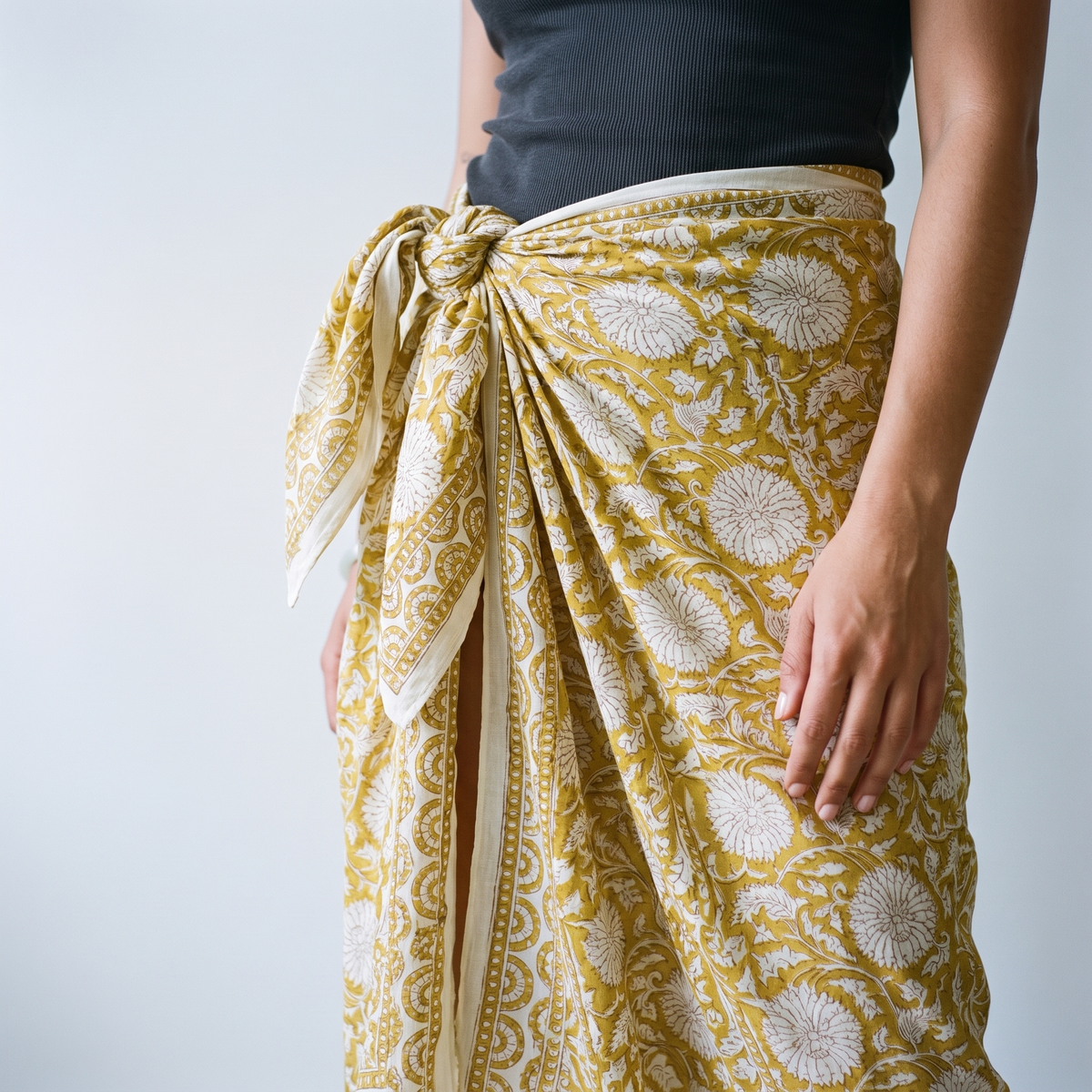 Détail du nœud du paréo Haldi à la hanche : plis du coton et bordure imprimée le long de l’ouverture