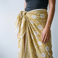 Détail du nœud du paréo Haldi à la hanche : plis du coton et bordure imprimée le long de l’ouverture