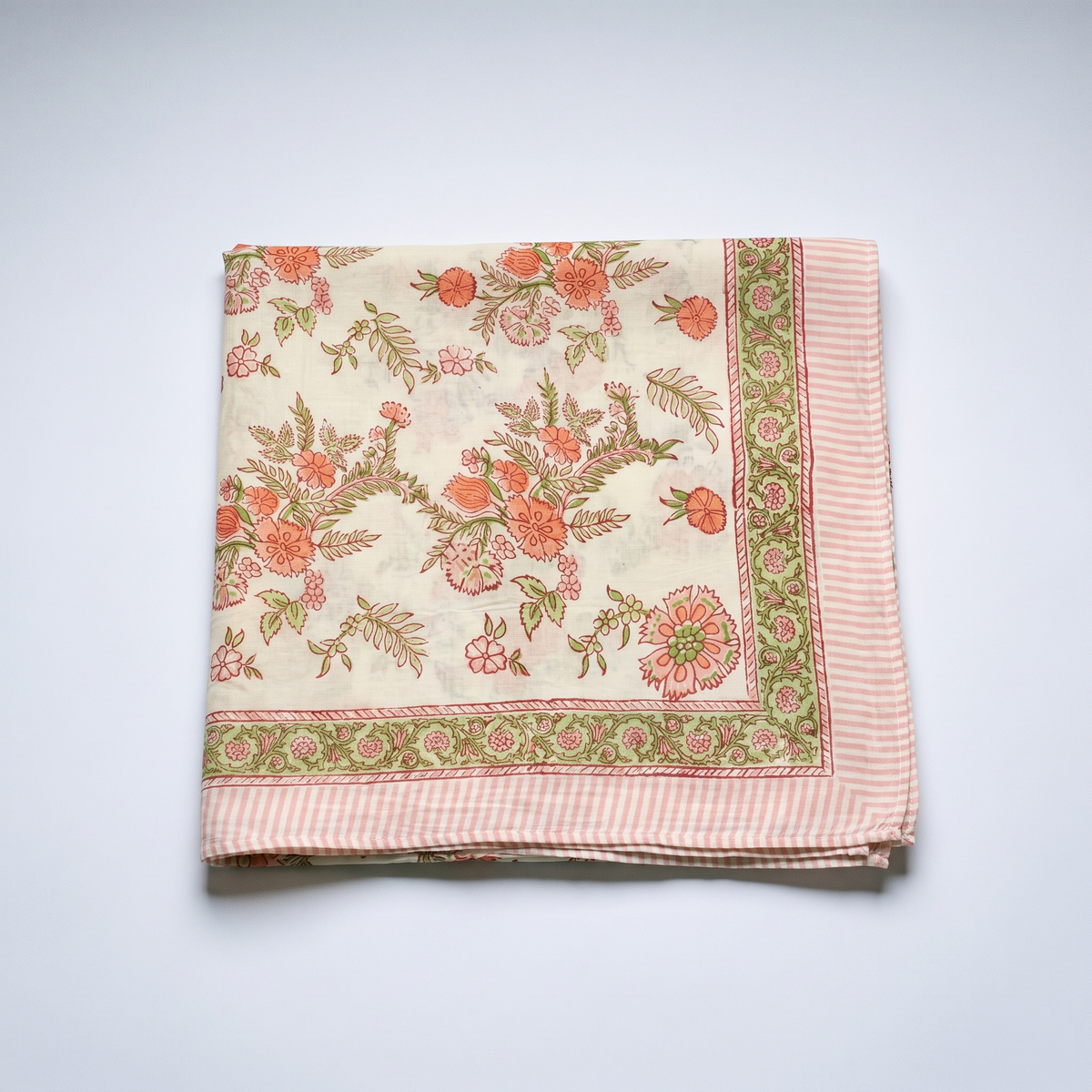 Paréo Champa plié à plat : coton blockprint, corolles corail et fougères vert amande sur crème, bordure rayée rose