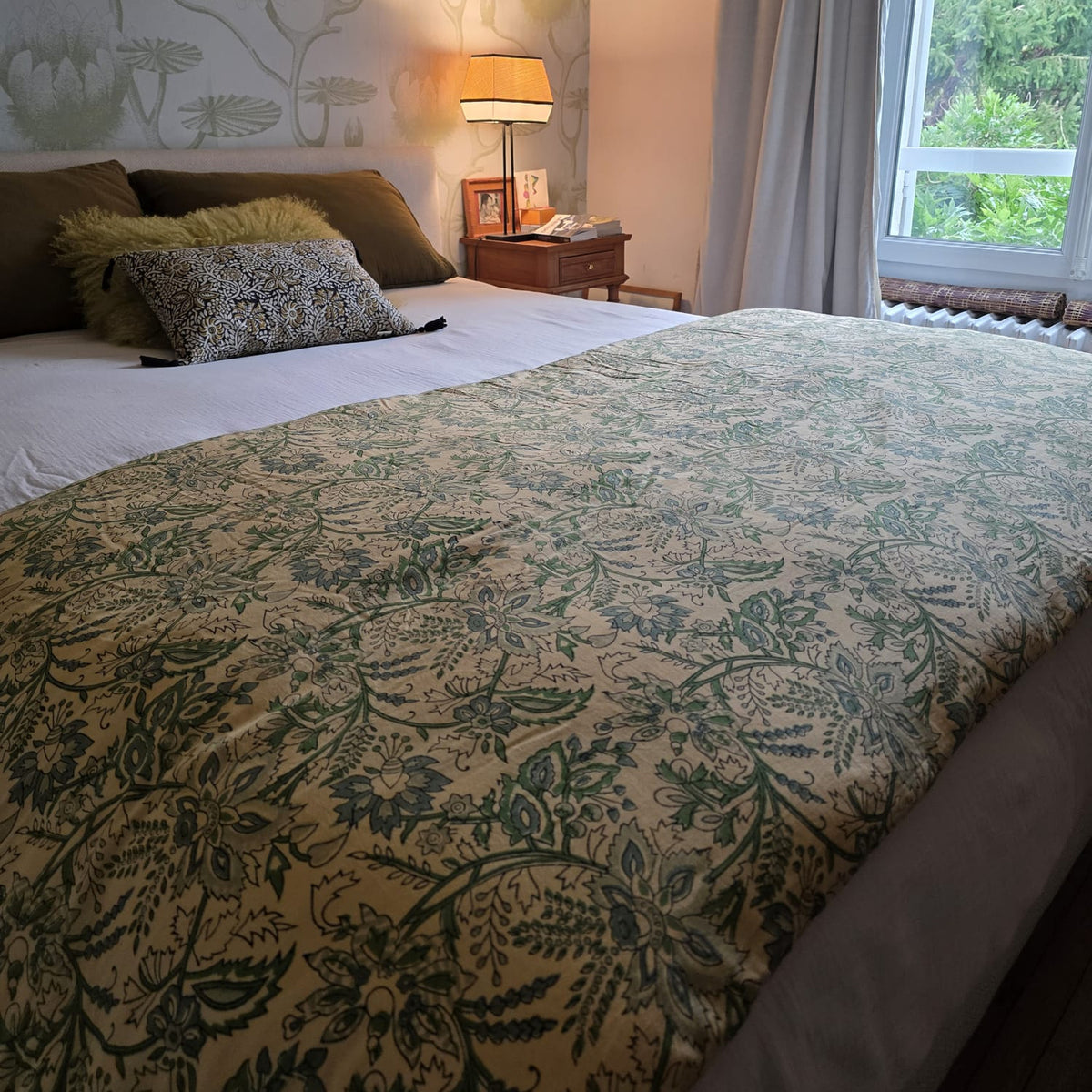 Housse d’édredon Jharna dépliée sur un lit : feuillage vert imprimé au bloc de bois sur coton écru