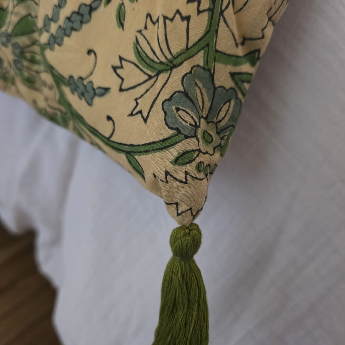 Détail d’un angle de la housse d’édredon Jharna : pompon vert mousse noué sur le coton imprimé