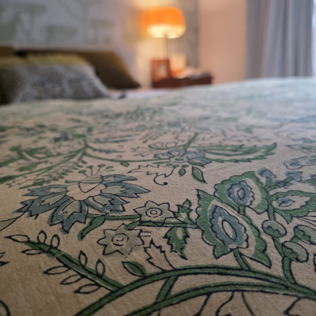 Gros plan du blockprint de la housse Jharna : fleurs et feuillage vert sur coton écru