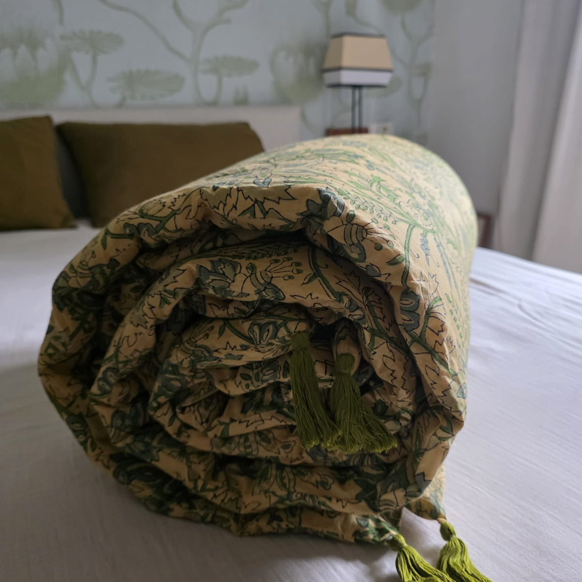 Housse d’édredon Jharna roulée sur un lit, au pied de la tête de lit