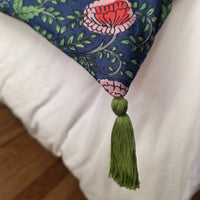 Détail d’un angle de la housse d’édredon Nilima : pompon vert olive noué sur le coton imprimé