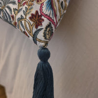 Détail d’un angle de la housse d’édredon Rupali : pompon bleu ardoise noué sur le coton imprimé