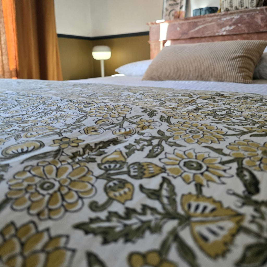 Le coton imprimé de la housse d’édredon Sevanti posé sur un lit, devant une cheminée de marbre rose