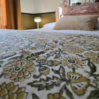 Le coton imprimé de la housse d’édredon Sevanti posé sur un lit, devant une cheminée de marbre rose