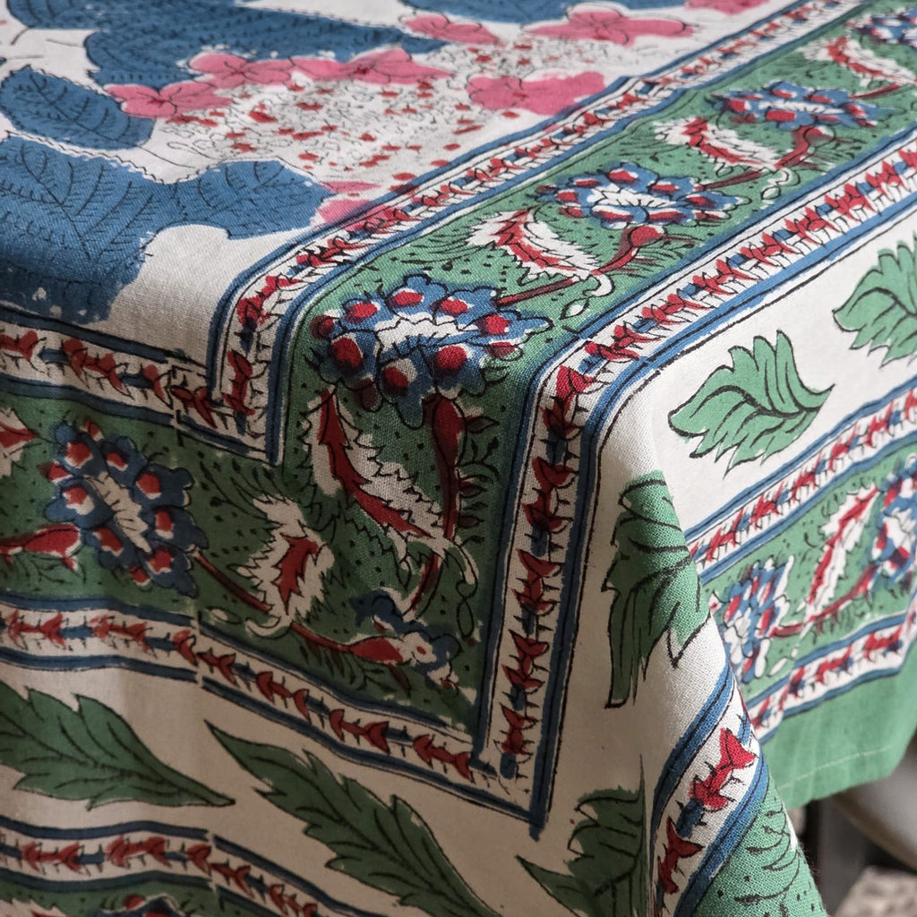 Coin de la nappe Anjana : la retombée et la frise de bordure, feuillage vert bouteille et fleurons rouge brique