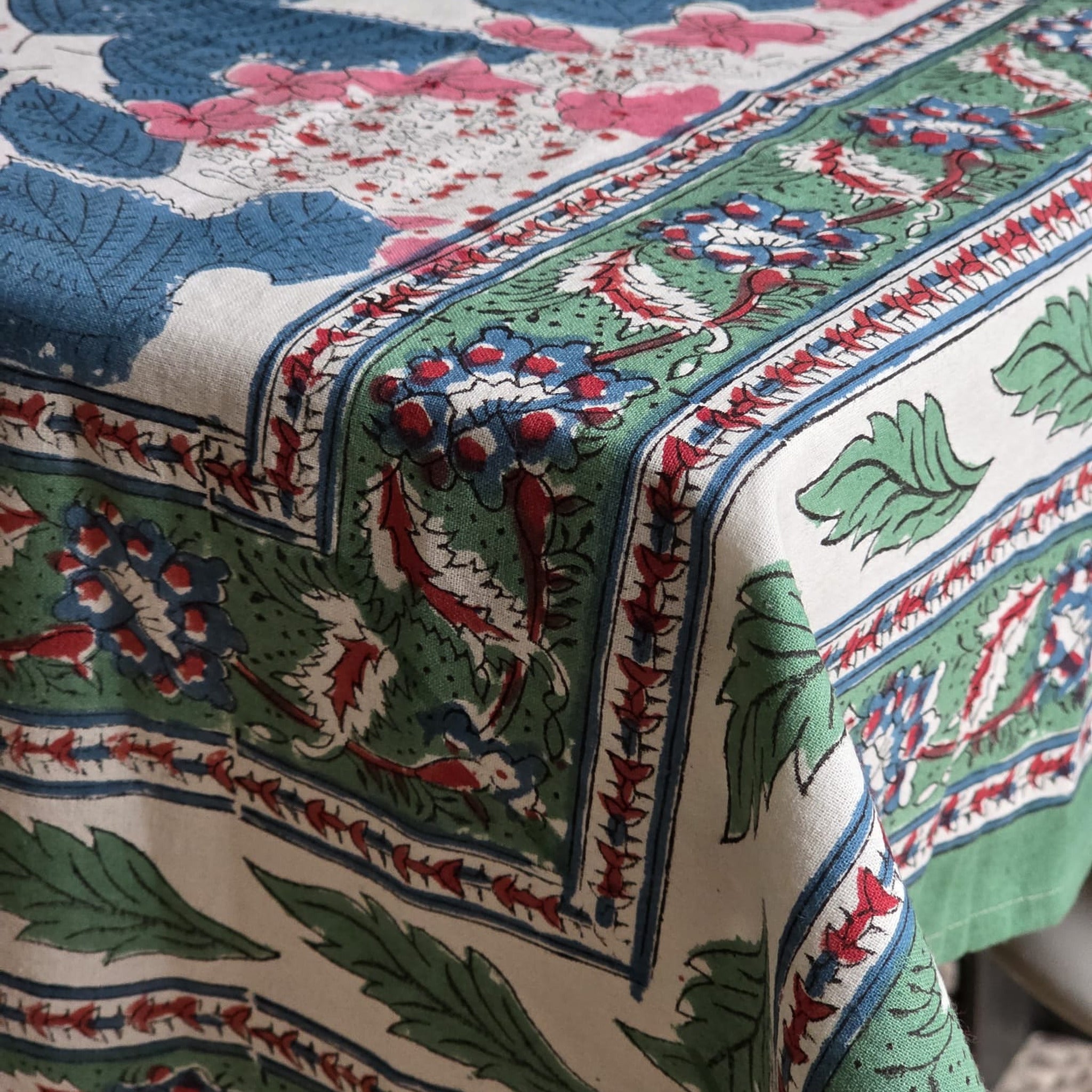 Coin de la nappe Anjana : la retombée et la frise de bordure, feuillage vert bouteille et fleurons rouge brique