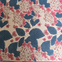 Détail du blockprint de la nappe Anjana : feuilles indigo nervurées et grappes de fleurs roses sur coton écru