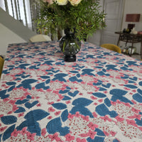 Nappe Anjana sur une grande table de salle à manger, dressée d’un bouquet de roses pâles