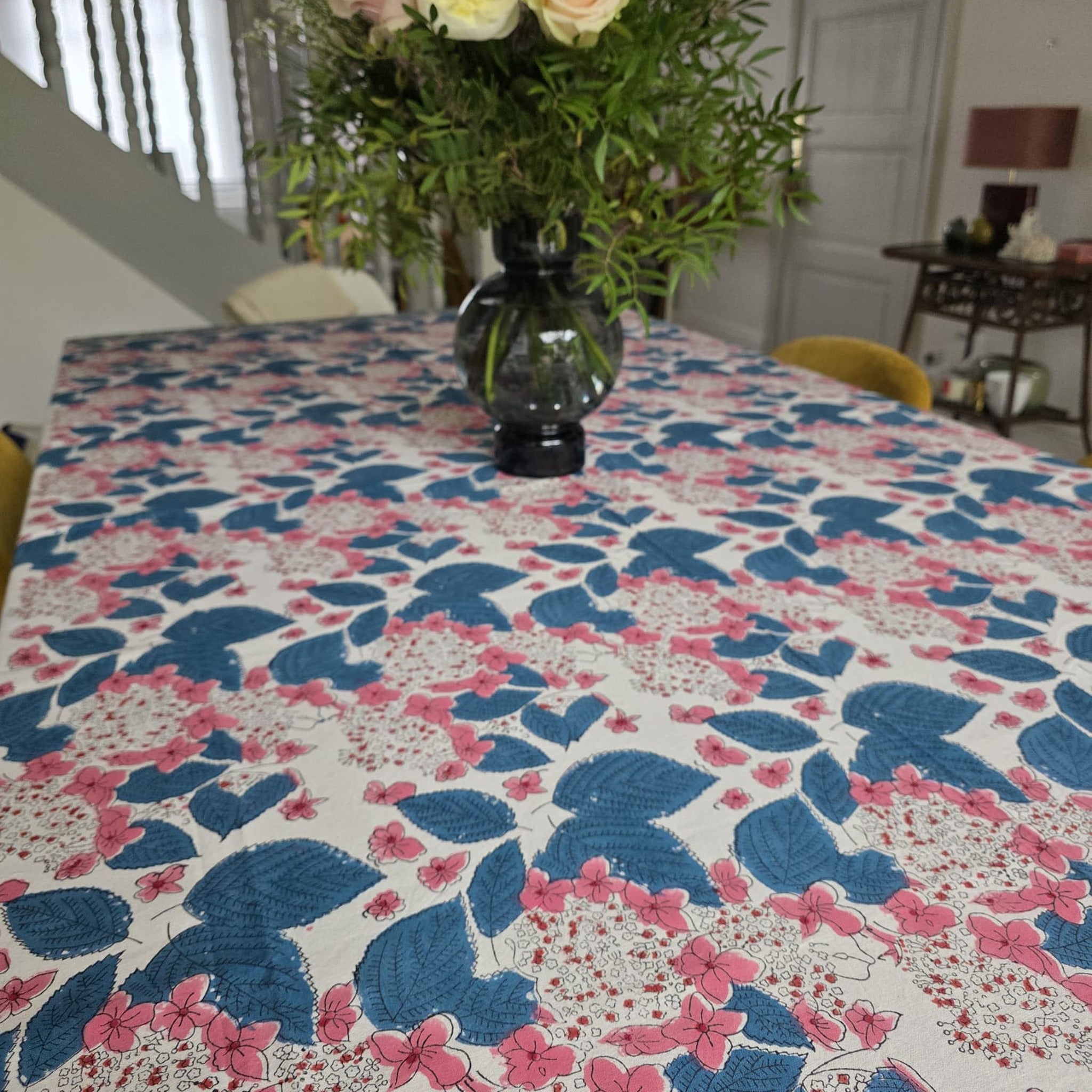 Nappe Anjana sur une grande table de salle à manger, dressée d’un bouquet de roses pâles