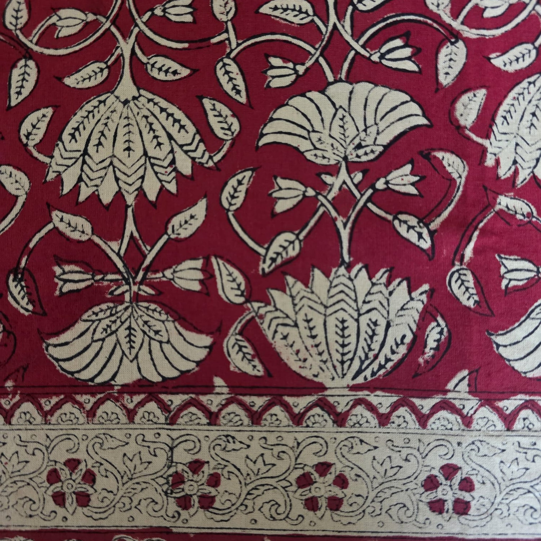Détail du blockprint de la nappe Arunima : treillis de tiges fines et palmettes écrues sur fond rouge