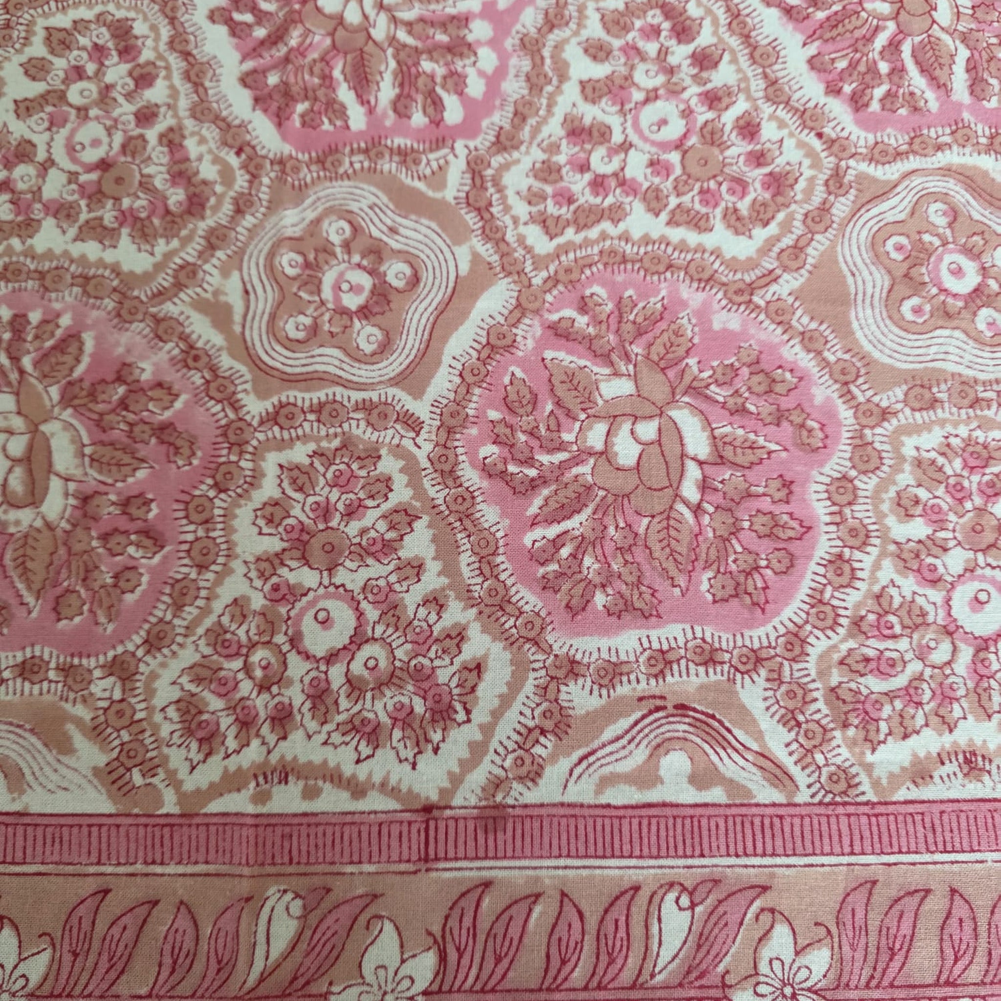 Détail du blockprint de la nappe Gulabi : médaillon floral rose ton sur ton et naissance de la bordure