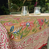 Nappe Madhu sur une table de jardin, jardin fleuri sur fond doré et bordure claire