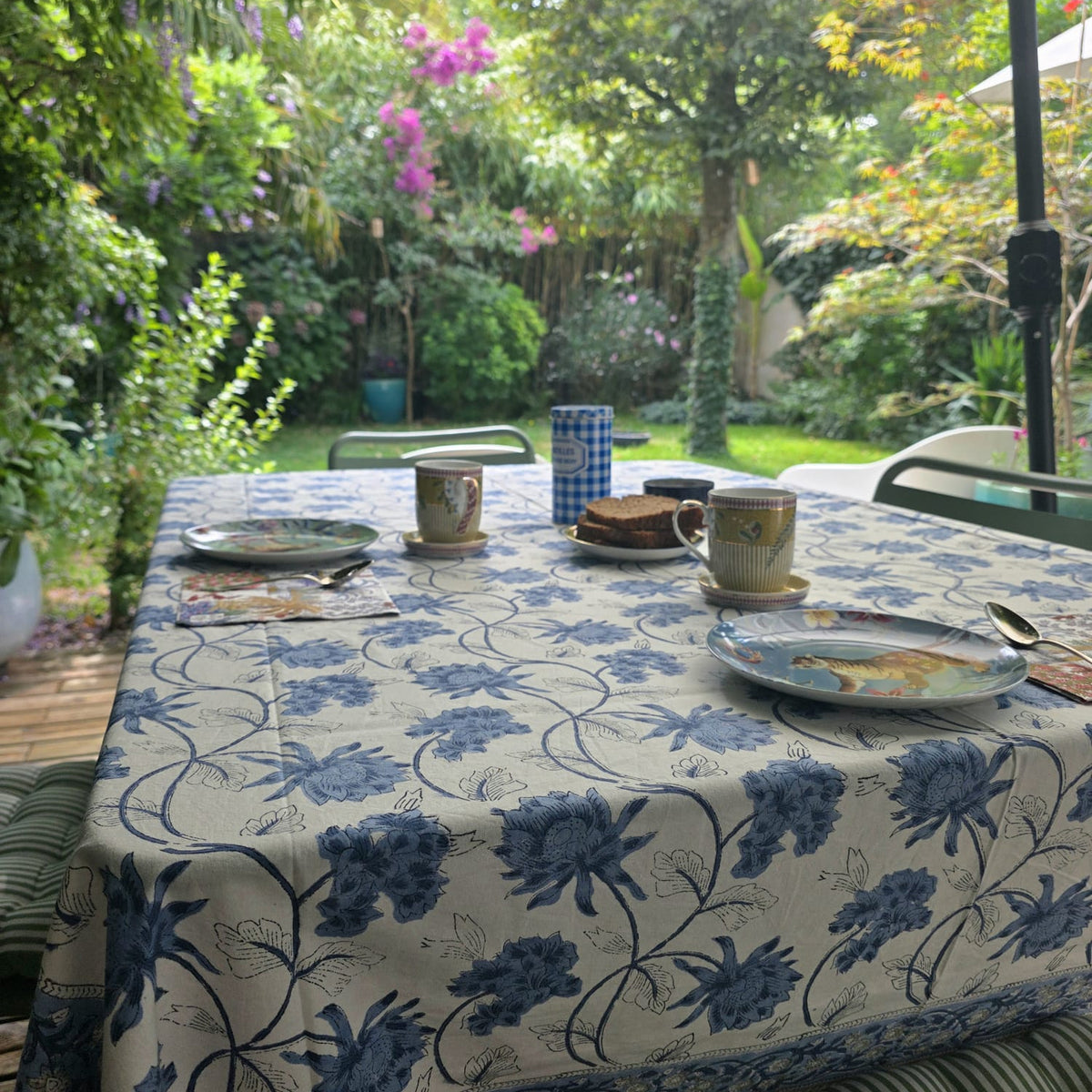 Nappe Meghna dressée sur une table de terrasse : grandes fleurs de chardon bleu porcelaine sur coton écru