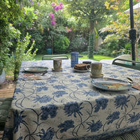 Nappe Meghna dressée sur une table de terrasse : grandes fleurs de chardon bleu porcelaine sur coton écru