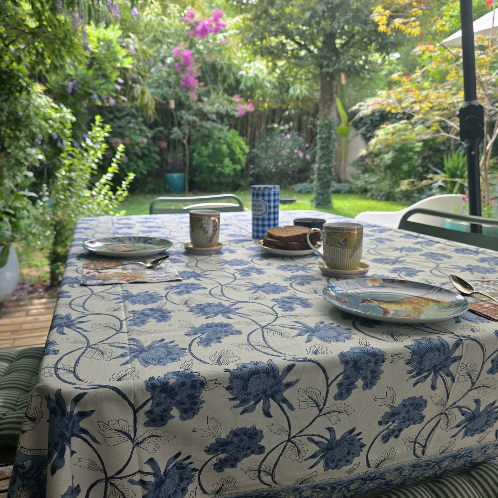 Nappe Meghna dressée sur une table de terrasse : grandes fleurs de chardon bleu porcelaine sur coton écru