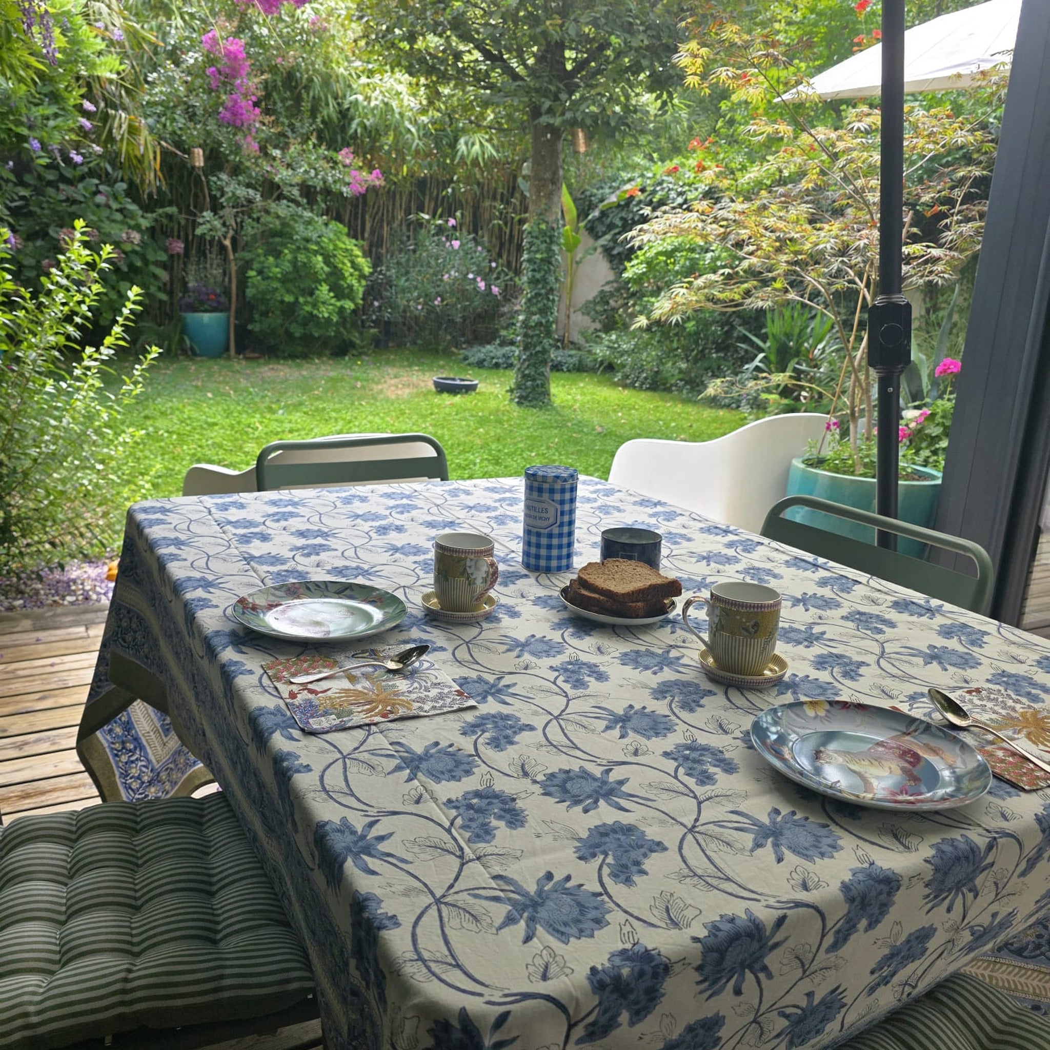 Nappe Meghna sur une table de terrasse dressée, sous un parasol, face au jardin