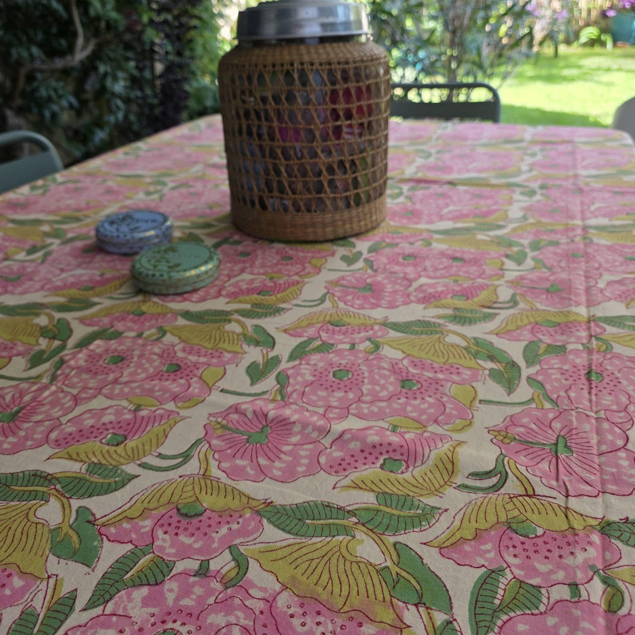 Nappe Pallavi dressée sur une table de jardin, grandes fleurs roses et feuillage anis sur coton écru