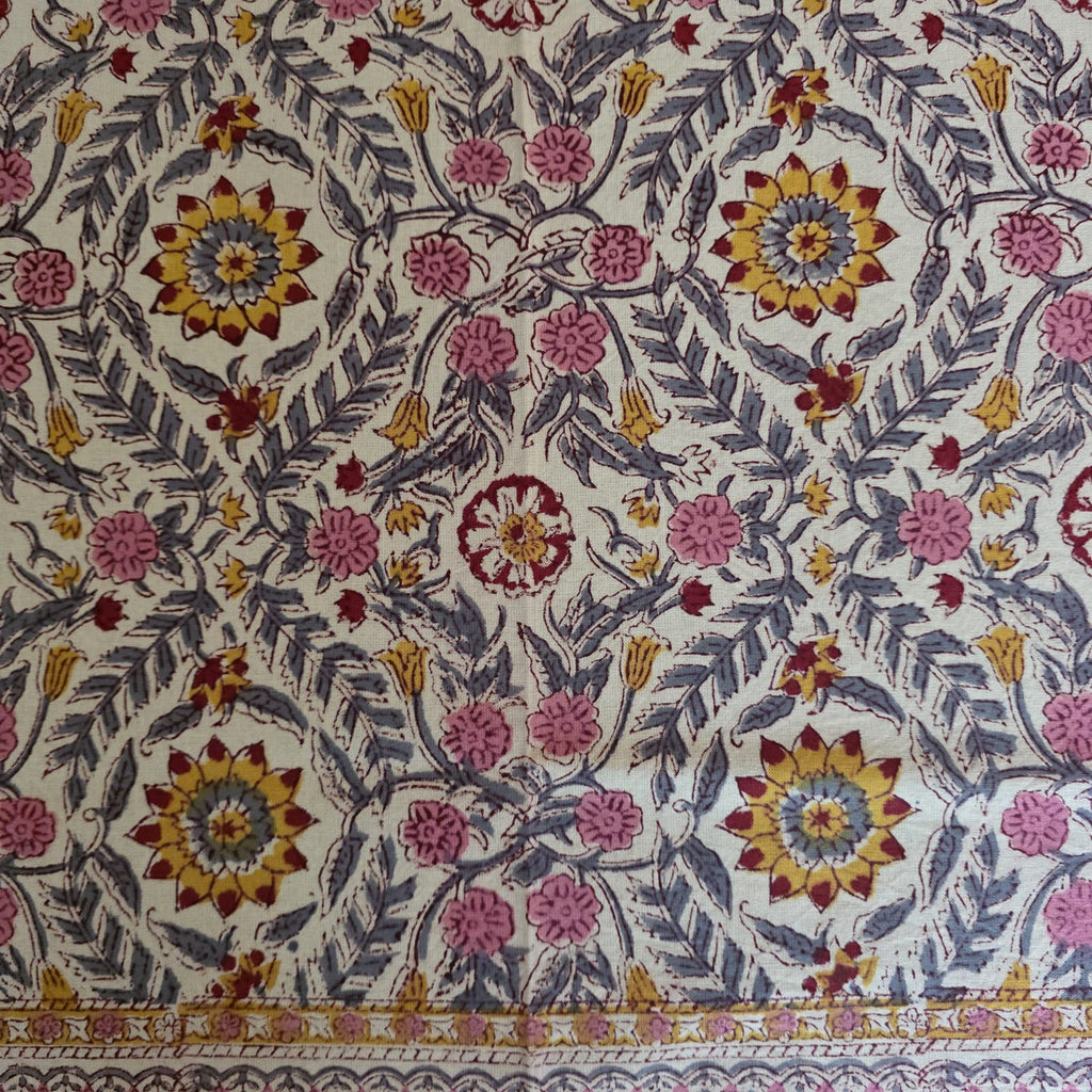 Détail du blockprint de la nappe Suman : rosaces safran à cœur rouge, fleurettes roses et feuilles ardoise